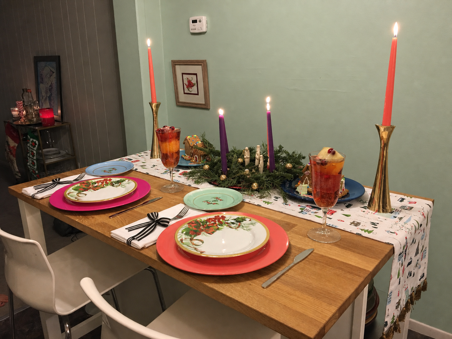 Christmas breakfast table with mint wall, coral and pink place settings, purple Advent candles, and gold candleholders