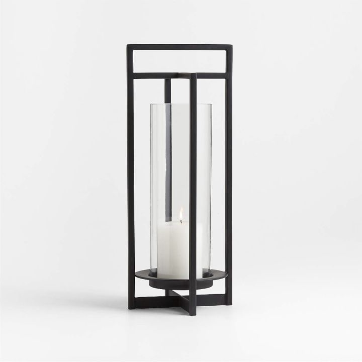 A large black metal outdoor lantern with an ivory candle.