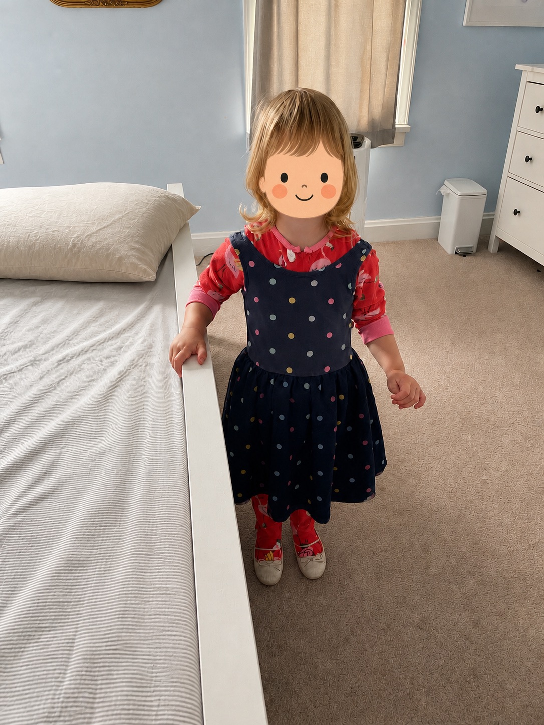 A young child proudly shows the outfit she put together, with her identity protected by an illustrated cartoon face.
